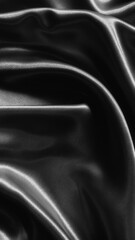 Fototapeta premium Luxurious black satin fabric flows with elegant folds, creating a sleek and sophisticated texture full of depth and shine.