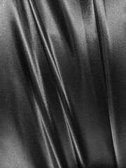 Fototapeta premium Luxurious black satin fabric flows with elegant folds, creating a sleek and sophisticated texture full of depth and shine.
