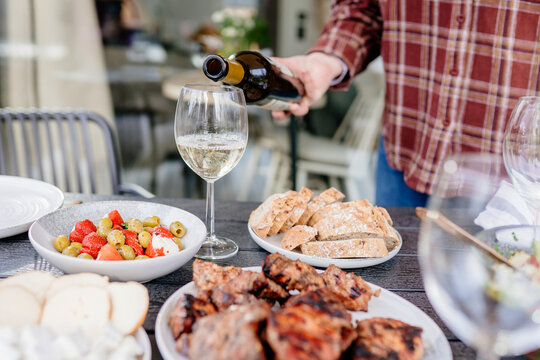 Unrecognizable blonde woman pouring white wine at outdoor cabin lunch