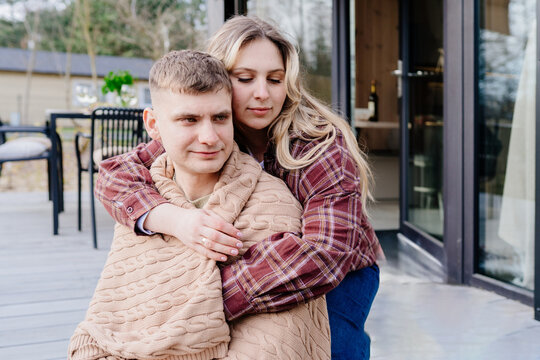 Young white couple wrapped in blanket on modern cabin terrace