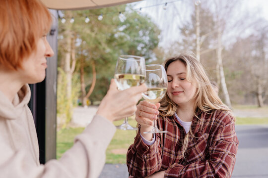 Two white women enjoying peaceful wine toast on cabin terrace