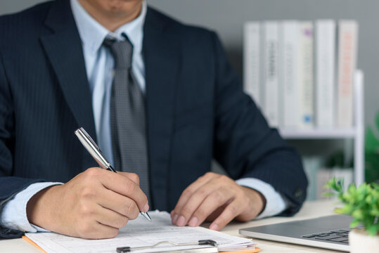 Manager hands holding pen filling application form clipboard desk. Human resources administration bureaucracy management hiring process corporate workspace laptop plant background.