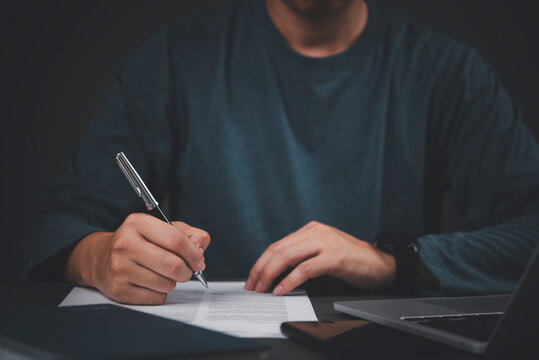 Man signing business contract document pen desk laptop legal agreement partnership corporate deal insurance policy loan paperwork official commitment real estate commercial investment