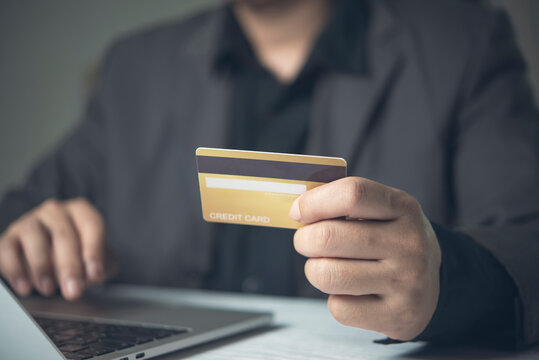 Businessman holding gold credit card typing laptop computer digital payment online shopping transaction ecommerce banking secure checkout internet purchasing corporate finance retail internet business
