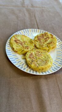 Three potato pancakes on plate, crispy golden draniki seasoned with pepper and herb flakes, served on patterned ceramic plate