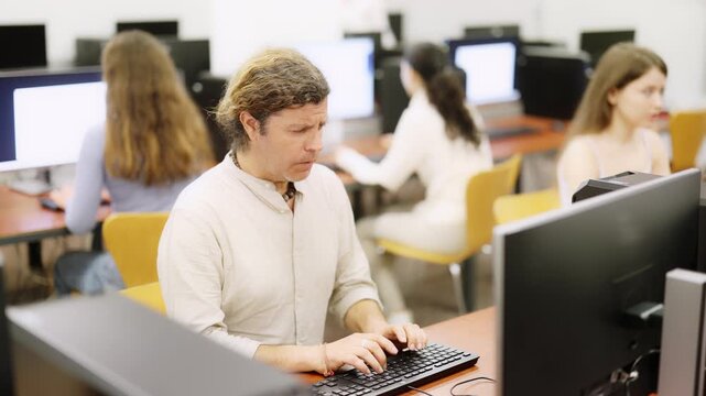 Man student of computer courses types on keyboard, performs work, educational practical task. Pupil performs educational tasks using computer