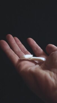 White non tobacco nicotine pouches slowly shown by a person's open palm against a dark studio background, highlighting a modern alternative to traditional smoking products