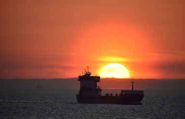 Obraz premium Frachtschiff fährt bei Sonnenaufgang in der Ostsee