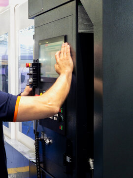 Worker Operating Industrial CNC Machine Touch Screen Control Panel in Manufacturing Facility