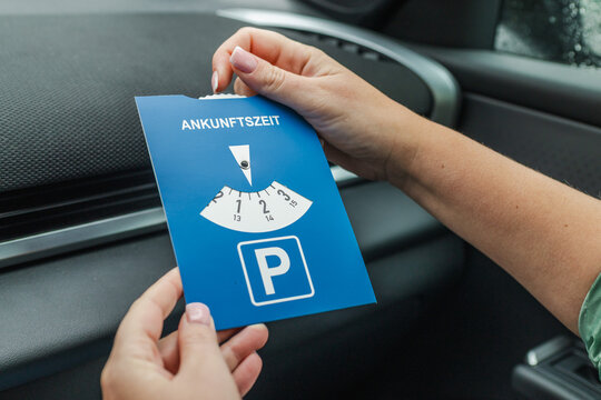 Female driver holding blue european parking disc inside modern vehicle