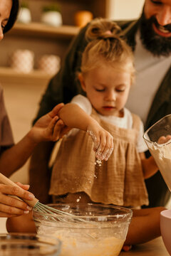 Family baking together in kitchen teaching child cooking