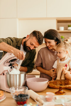 Family making dessert together in modern kitchen