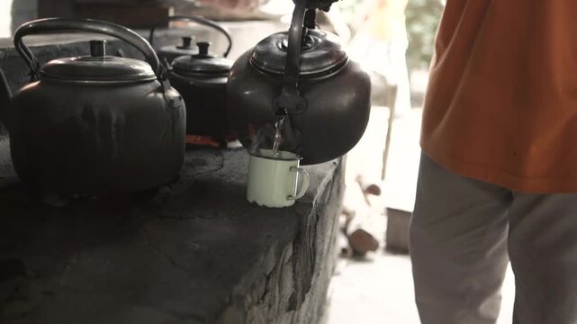 Interior perspective of a rustic kitchen showing large traditional metal steaming pots or cauldrons