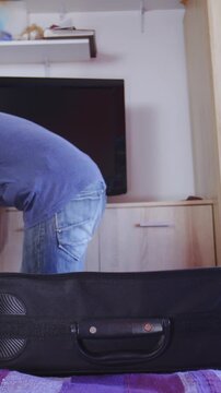 Man packs clothes into travel case and leaves