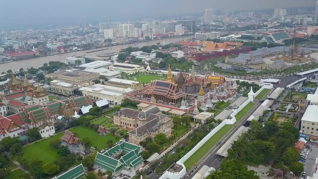Cinematic aerial drone shot with subtle orbital movement above a historic temple complex in Bangkok, Thailand. Scenic urban travel footage featuring traditional Thai architecture, the Chao Phraya Rive