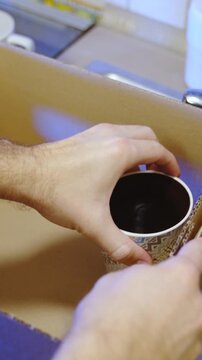 Packing mugs and cups into box for moving out