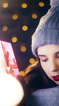 Young woman check the Christmas present box hearing what is inside