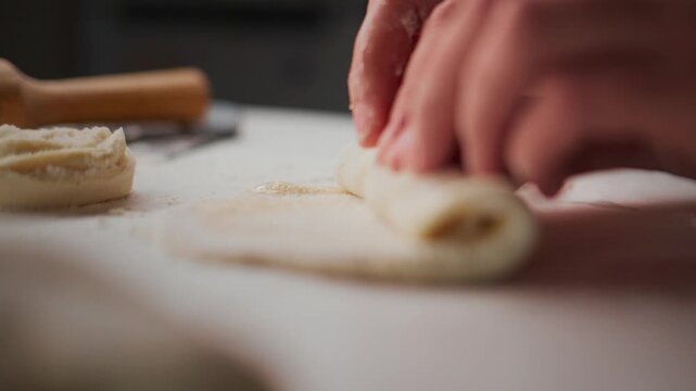 Hands gently roll dough on a floured surface. Focus on careful, precise motion. Ideal for food preparation or cooking tutorials. Evokes calm, methodical energy. Can be used for baking, pastry
