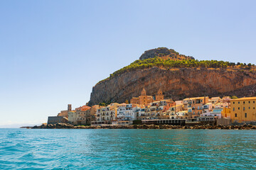 Naklejka premium View from the boat of Cefalù, Metropolitan City of Palermo, coastal town in northern Sicily, Italy. Old buidings, the Duomo, a Norman Cathedral and La Rocca, august 2023.