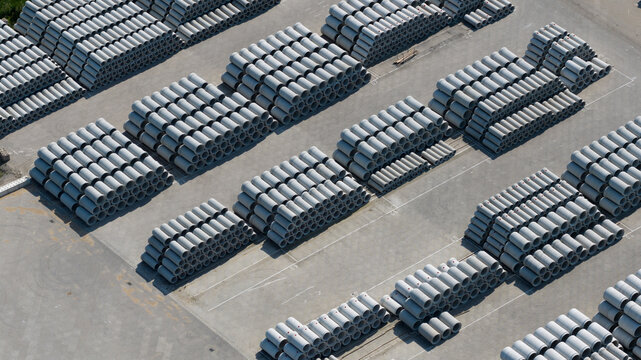 Aerial view of neatly stacked concrete pipes in an industrial storage yard with geometric patterns and grey textures Oosterhout, North Brabant, Netherlands.