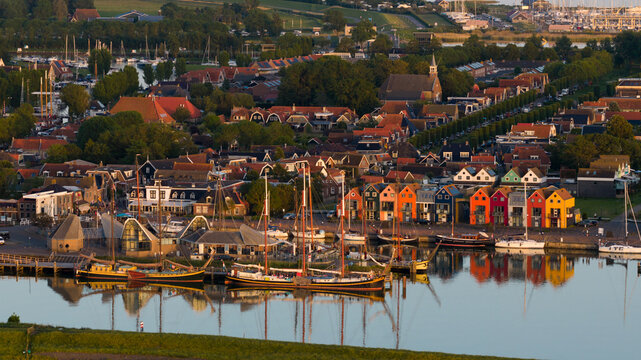 Aerial view of colorful waterfront houses and traditional sailing ships docked in the harbor during golden hour Stavoren, Friesland, Netherlands.