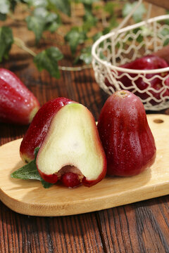 Fresh Red Wax Apples from Hainan - Tropical Bell-Shaped Fruit with Water Droplets on Wooden Board
