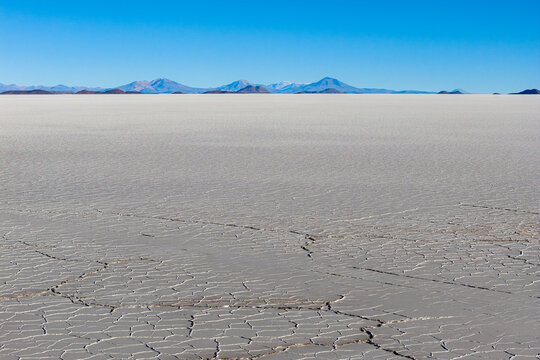 Aerial view of Uyuni Salt Flat showing hexagonal salt crust patterns and distant mountains under a clear blue sky Potosi Department, Bolivia.