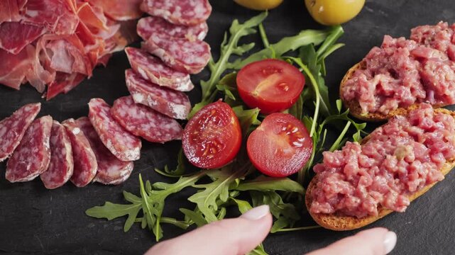 Assortment of various tasty Spanish appetizers. Meat, dried sausage, olives, tomatoes, steak tartare with bread. High quality 4k footage
