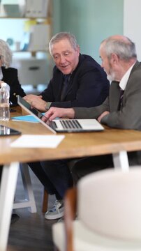 Senior male leader sits at table, talking with subordinate employees - discussing the company development strategy. High quality 4k footage
