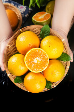 Fresh Orange Citrus Fruits from Hubei Zigui Region in Bamboo Basket with Cut Pieces Showing Vitamin-Rich Flesh