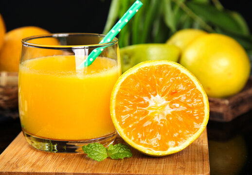 Fresh Orange Juice with Cut Orange Pieces and Mint on Wooden Board - Healthy Summer Drink Rich in Vitamins