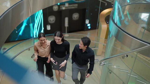 Ascent to Innovation: Three professionals ascend a modern, illuminated staircase, signifying progress and forward-thinking in a contemporary corporate environment.