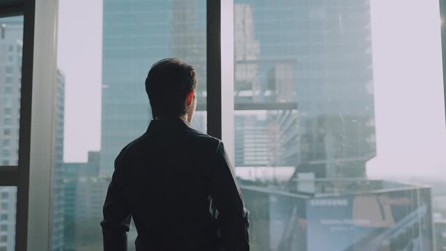 Ambition Gazes Out: A man in a sharp suit stands before a panoramic window, his back to the camera, overlooking a sprawling cityscape at dawn, symbolizing aspiration and future possibilities.