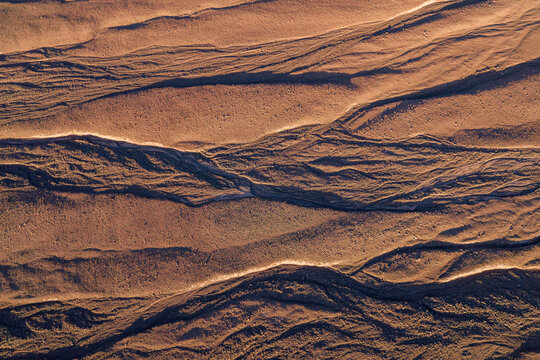 Aerial view of intricate erosion patterns and dry riverbeds in the arid desert landscape during golden hour San Pedro de Atacama, Antofagasta, Chile.