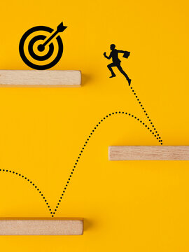 Businessman jumping towards target representing career growth and challenges