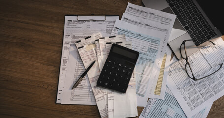 Tax forms, receipts, and calculator arranged on a desk with financial documents and laptop, supporting tax preparation, accounting review, expense calculation, and tax filing workflow. © onephoto