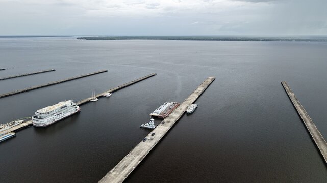 Aerial view of ships and barges docked at long concrete piers on the St. Johns River under an overcast sky in Green Cove Springs, Florida, United States.