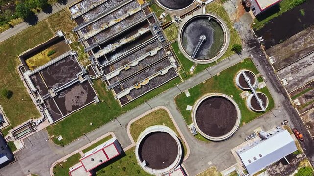 Aerial stormdamaged wastewater plant showing flooded clarifiers and debris emergency response and environmental engineer team mapping contamination risks