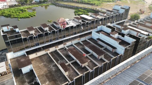An aerial view showing a row of modern shop houses with glass facades and dark-colored roofs along the edge of a large lake in Indonesia.
