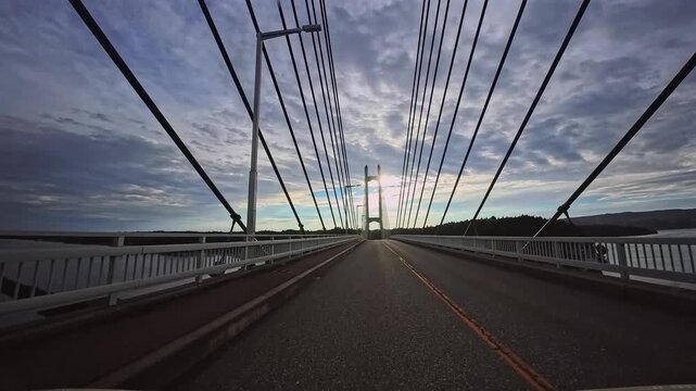 Driving across Twin Bridge Noto at sunset with bridge cables converging overhead in Ishikawa Japan