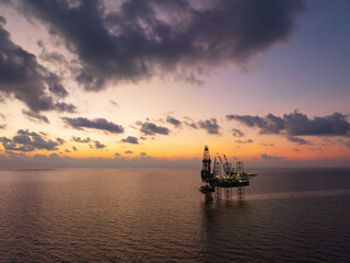 Obraz premium Aerial View of Offshore Jack-Up Rig and Production Platform at Sunset.