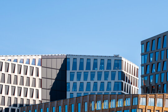 Office building architecture spreads beneath blue sky, where geometric facade grids and urban windows create a clean commercial skyline edge.