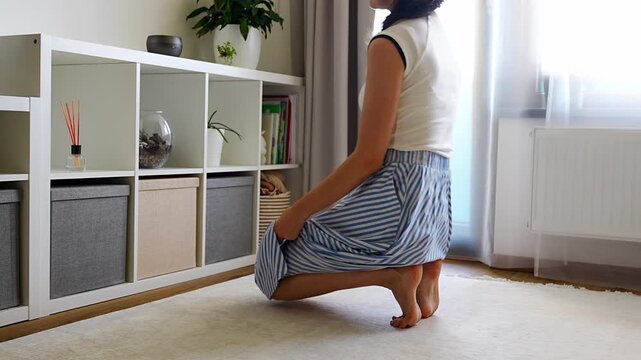 Young woman using storage box from shelving system in home interior. Home organization and decluttering routine concept