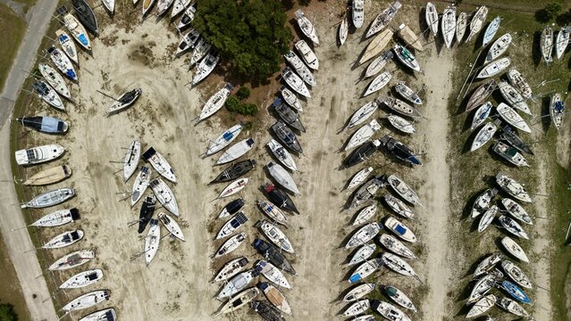 Aerial view of numerous sailboats parked in organized rows at a dry dock storage facility under bright sunlight in Green Cove Springs, Florida, United States.