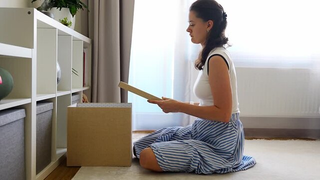 Young woman closing and putting away storage box after organizing belongings in modern home interior. Home organization and decluttering routine concept