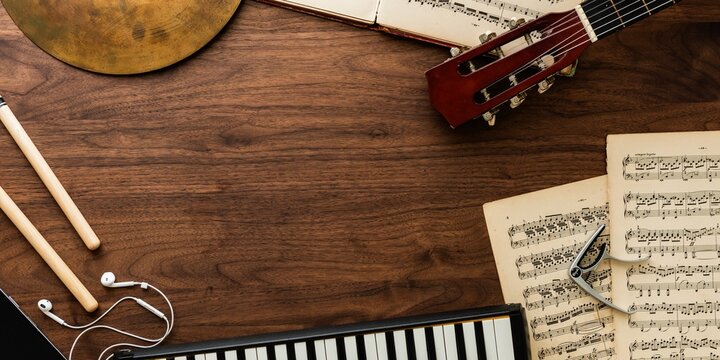 Musical instruments and sheet music on a wooden table, top view.