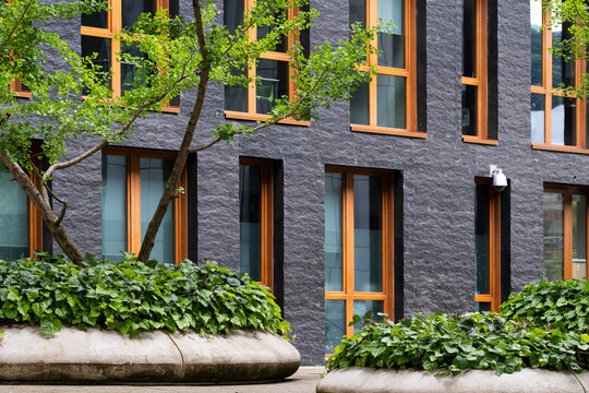 Brick facade architecture with windows and planters anchors the building in vegetation, adding urban exterior detail to a clean frontage.