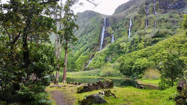Scenic landscape of cascading waterfalls and lush green valley at Poco da Ribeira do Ferreiro on Flores Island in the Azores Portugal