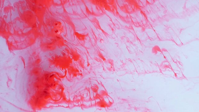 Microscopic view of red organic shapes moving through fluid creating an abstract biological texture suitable for medical or scientific research visualizations in a moody lighting style.