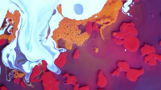 Vibrant pink, purple, and yellow ink drops expanding and mixing in a white fluid. High-energy organic cellular captured in a top-down view for experimental art visuals.